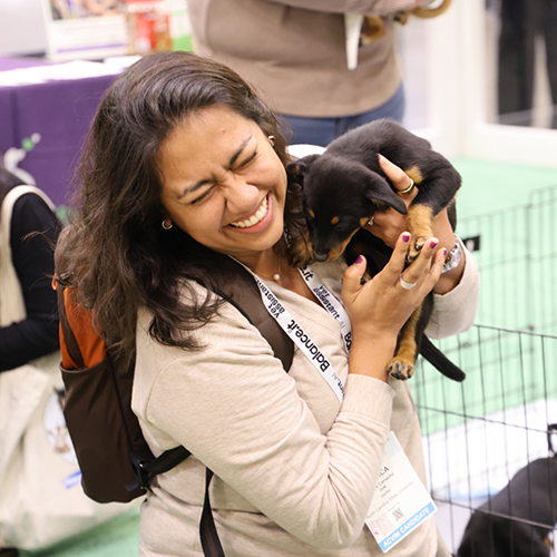 Person grinning holding a puppy