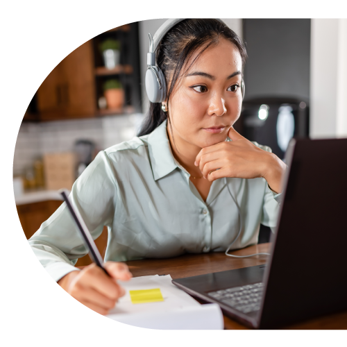 Person at a desk, looking at computer and taking notes.